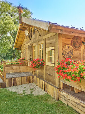 Traditionelles Holzhaus mit blühender Fensterbank, ideal für eine entspannte Auszeit.