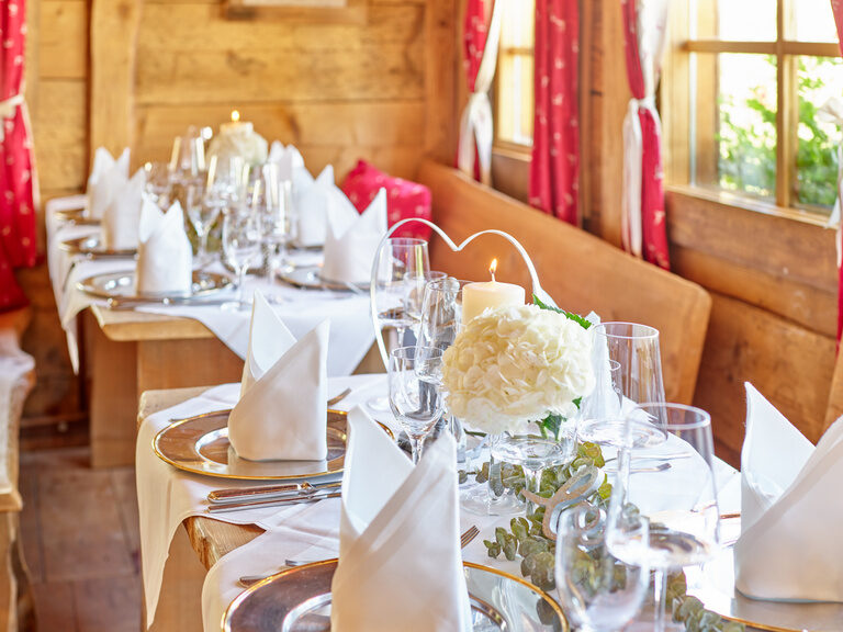 Stilvoll gedeckter Hochzeitstisch mit Kerzen und Blumenarrangements für eine unvergessliche Hochzeit im Gutshof in Bayern.