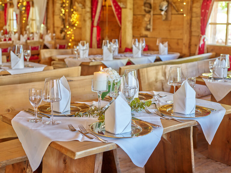 Elegante, rustikale Tischdekoration in einem gemütlichen Restaurant mit weißen Servietten und Kerzen.