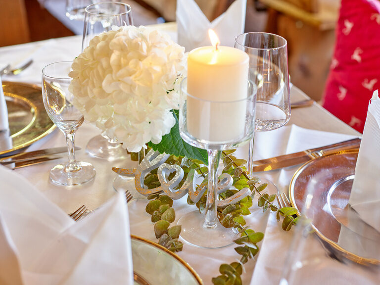 Detailaufnahme eines Hochzeitstisches mit Blumen und Kerzen, passend für eine elegante Hochzeit im Gutshof in Bayern.