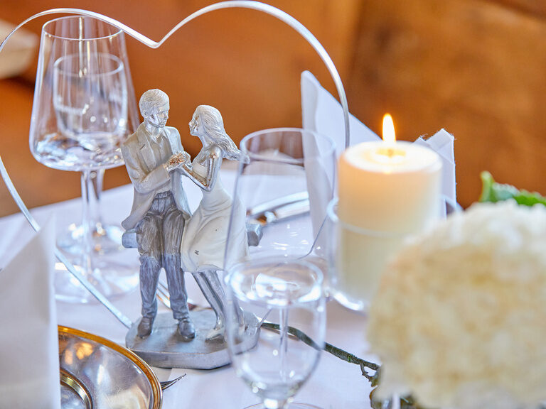 Herzförmige Tischdeko mit Brautpaarfigur, ein liebevoll gestaltetes Detail für eine Hochzeit im Gutshof in Bayern.
