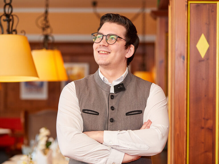 Stolzer Mitarbeiter in Tracht im stilvollen Restaurant.
