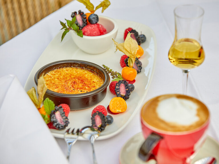 Eine Dessertvariation mit Crème Brûlée, frischen Beeren, Sorbet und Cappuccino, präsentiert im Gutshof bei Bad Griesbach.
