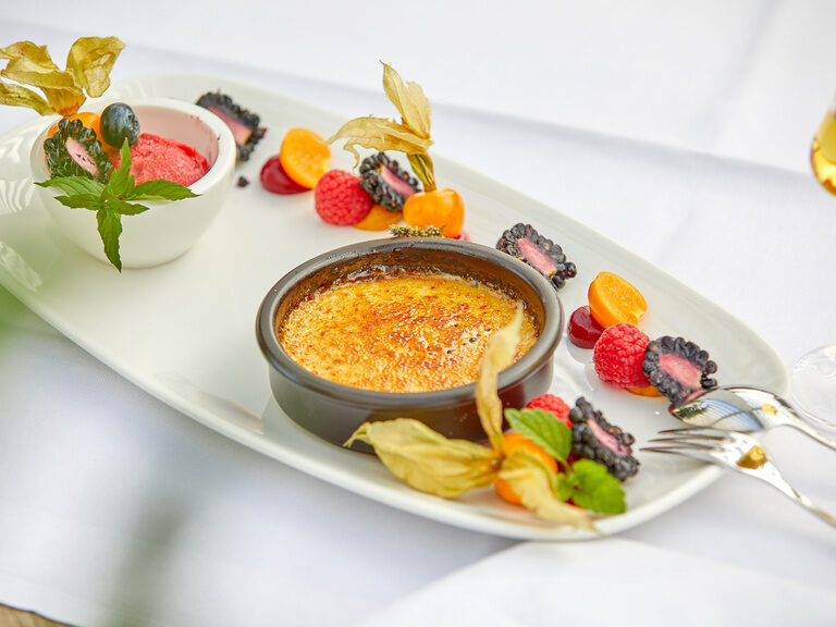 Köstliches Dessert mit Crème brûlée, frischen Früchten und Sorbet, ein Highlight der Gastronomie bei Bad Griesbach.