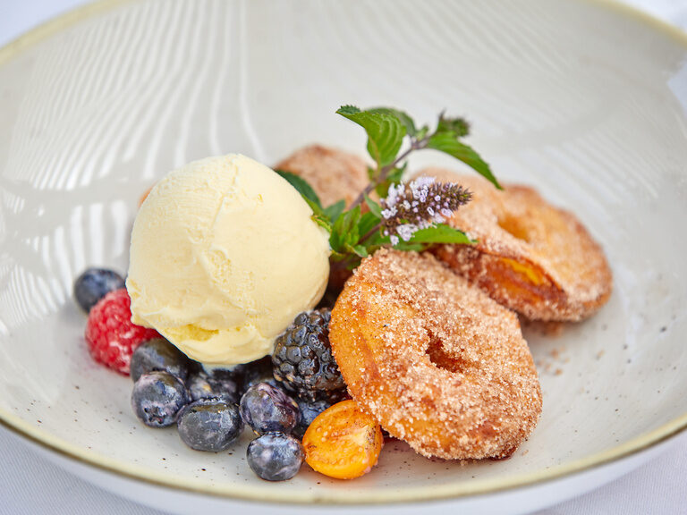 Ein Dessert mit gebackenen Teigstücken, Vanilleeis und frischen Beeren, serviert im Restaurant.