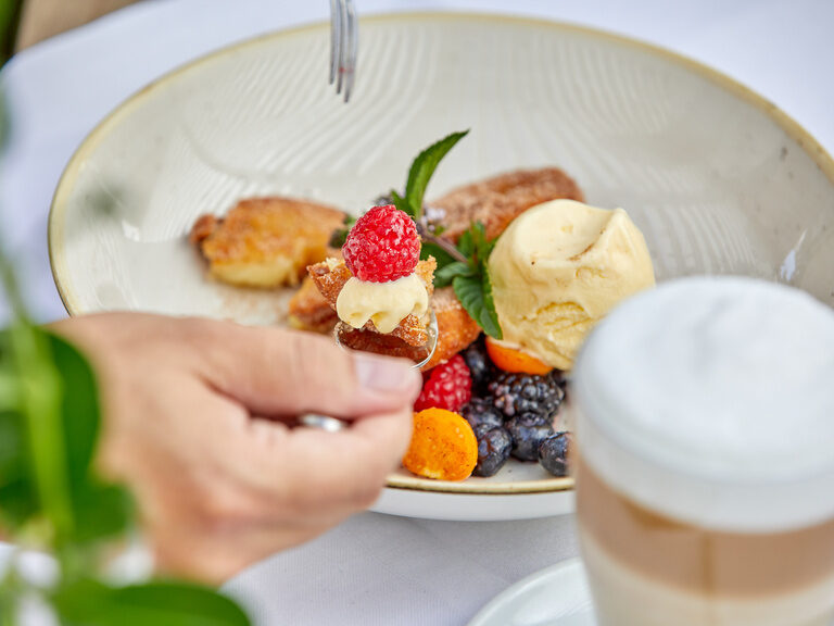 Ein Dessertteller mit warmen Köstlichkeiten, frischen Beeren, Vanilleeis und einem Latte Macchiato.