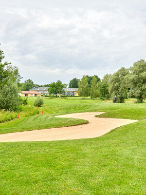 Eine malerische Golflandschaft mit Fairways, Sandbunkern und umgeben von Bäumen und einer ruhigen Umgebung.