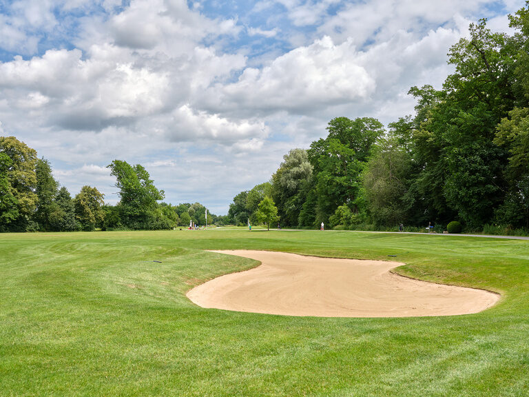 Golfplatz in der Nähe von Bad Griesbach mit weitläufigem Fairway, gepflegtem Rasen und einem Golfcart im Hintergrund.