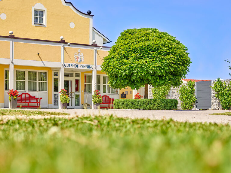 Elegantes Hotel inmitten eines Golfplatzes, idyllisch gelegen am Wasser mit grünen Fairways und Bäumen im Hintergrund.
