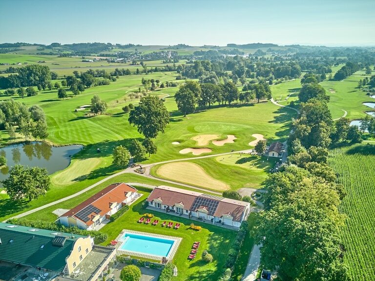 Blick auf das Hotelgelände mit Golfplatz und Pool, umgeben von grüner Landschaft – ideal für eine erholsame Zeit in der Natur.