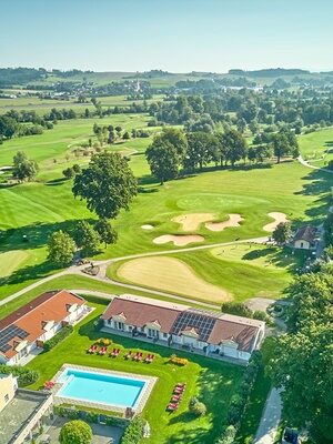 Blick auf das Hotelgelände mit Golfplatz und Pool, umgeben von grüner Landschaft – ideal für eine erholsame Zeit in der Natur.