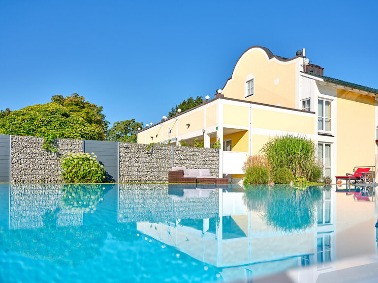 Hotelgarten mit Pool und sonnigem Himmel. Entdecken Sie Jobs bei Bad Griesbach und genießen Sie die Natur.