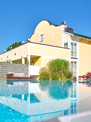 Poolspiegelung des Hotelgebäudes mit grünen Pflanzen im Vordergrund.