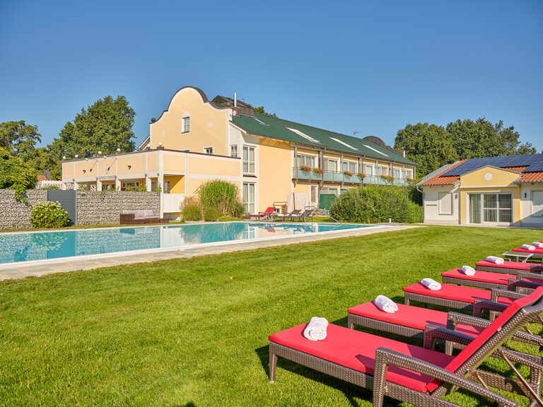 Blick auf den Gutshof bei Bad Griesbach und den Außenpool des Hotels an einem sonnigen Tag.