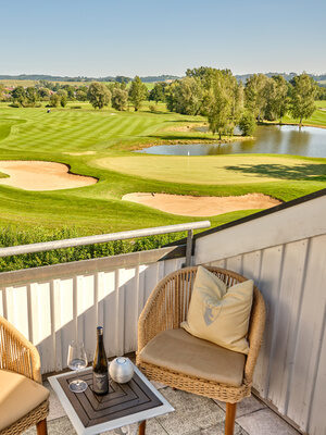 Blick auf den Golfplatz von einem Balkon mit gemütlicher Sitzgelegenheit.