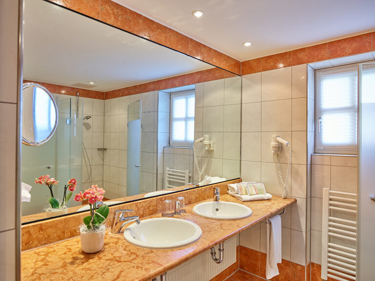 Ein modernes Badezimmer mit Doppelwaschbecken, großer Spiegelwand und stilvollen Details.