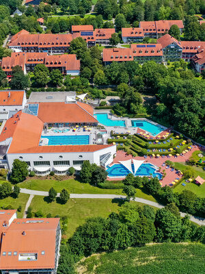 Thermenanlage mit Außenpools, Liegewiesen und umliegender grüner Landschaft.