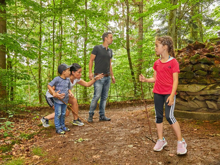 Eine Familie spielt im Wald, Kinder und Eltern sind aktiv und lernen die Natur zu schätzen.