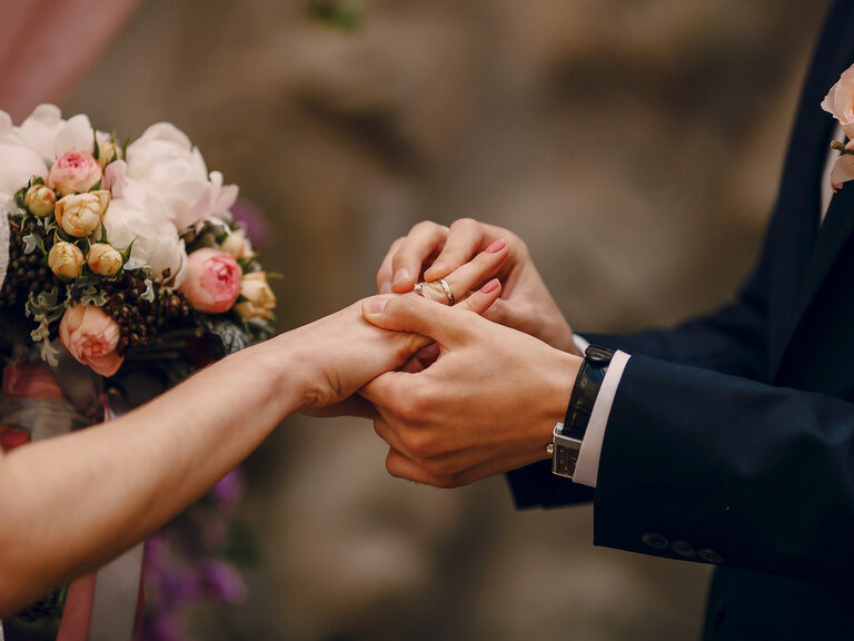 Nahaufnahme eines Hochzeitspaares beim Ringtausch, ein unvergesslicher Moment bei Feiern im Gutshof.