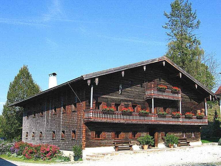 Historisches Bauernhaus mit Blumen geschmückten Balkonen, ein charmantes Beispiel für Ausflugsziele in Niederbayern.