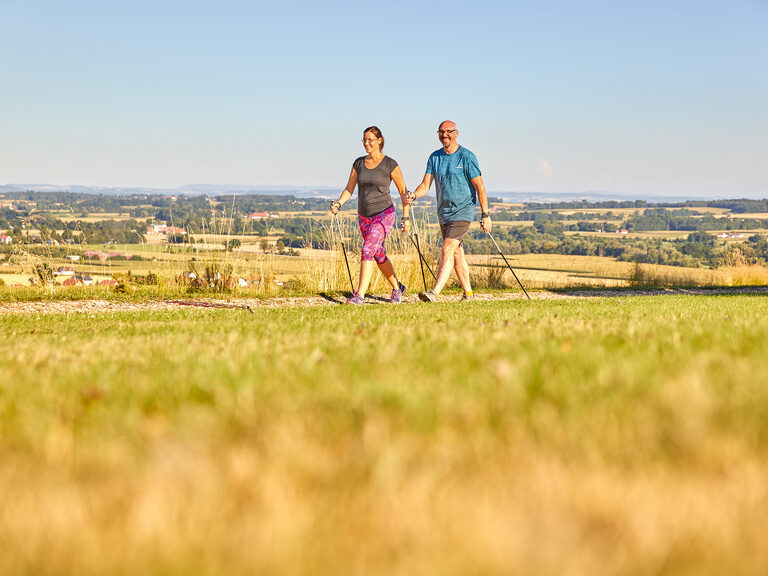 Zwei Personen mit Nordic-Walking-Stöcken erkunden die weitläufige Landschaft beim Wandern bei Bad Griesbach.