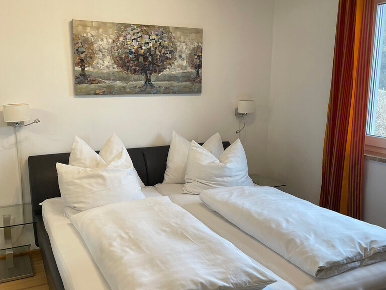 Schlafzimmer mit Doppelbett, weißer Bettwäsche und modernem Kunstbild an der Wand.