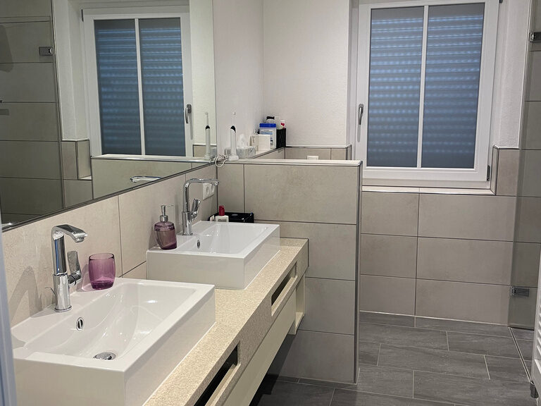 Modernes Badezimmer mit zwei Waschbecken, großem Spiegel und Fenster.
