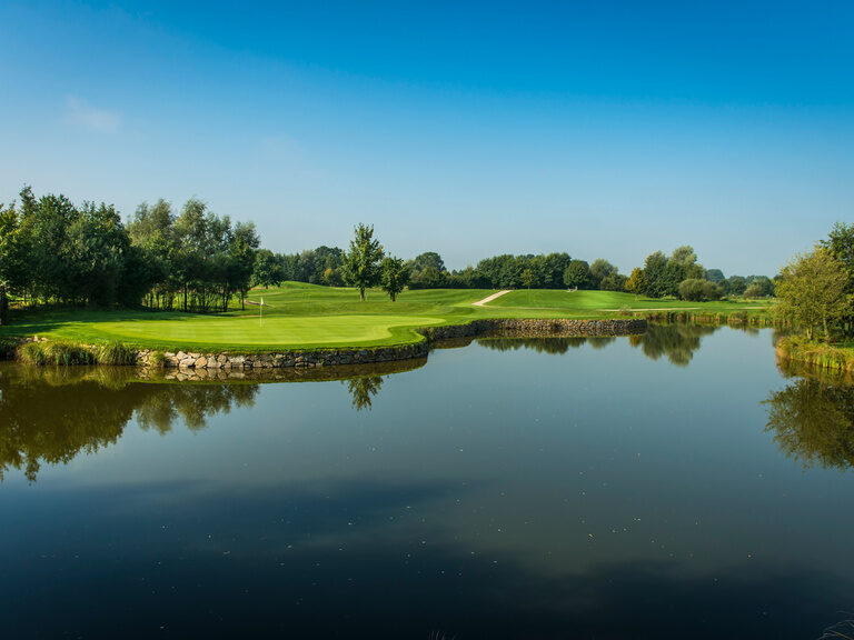 Der Porsche Golfplatz  mit großem Teich und umliegendem Grün.