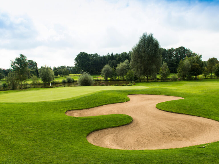 Ein weitläufiger Golfplatz mit Sandbunker und Bäumen – ein Highlight für Golfarrangements bei Bad Griesbach.