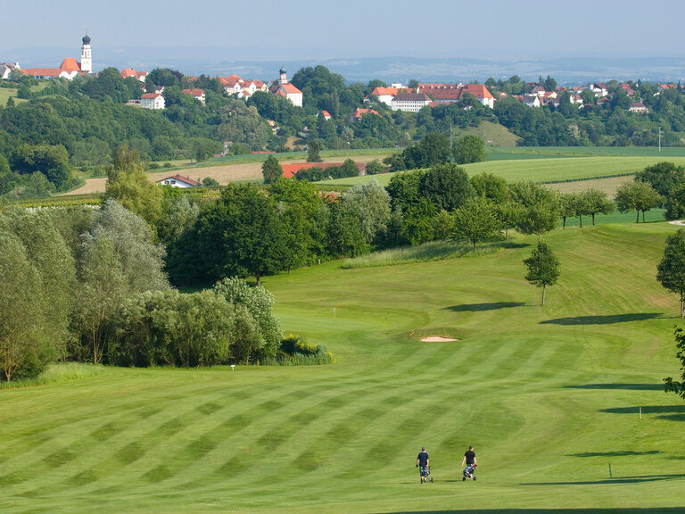 Zwei Golfer gehen auf gepflegtem Grün eines Golfplatzes in der Nähe von Bad Griesbach.